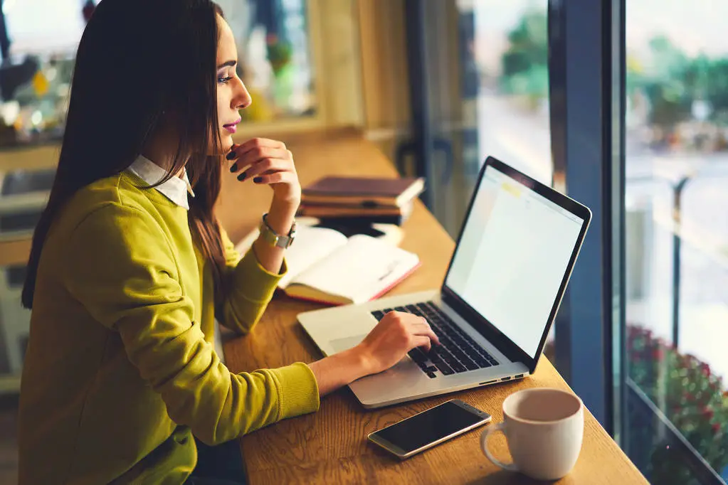 Professional female graphic designer modeling outlay using application on laptop computer with mock up screen